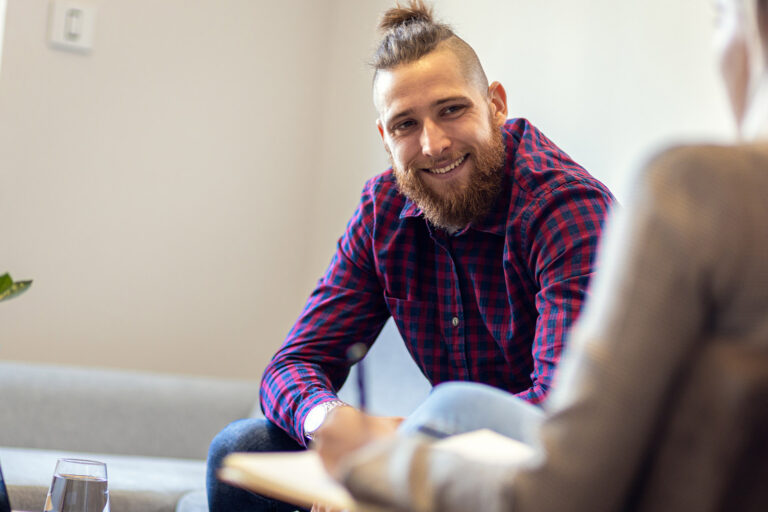 Young man talking to female psychologist during session.